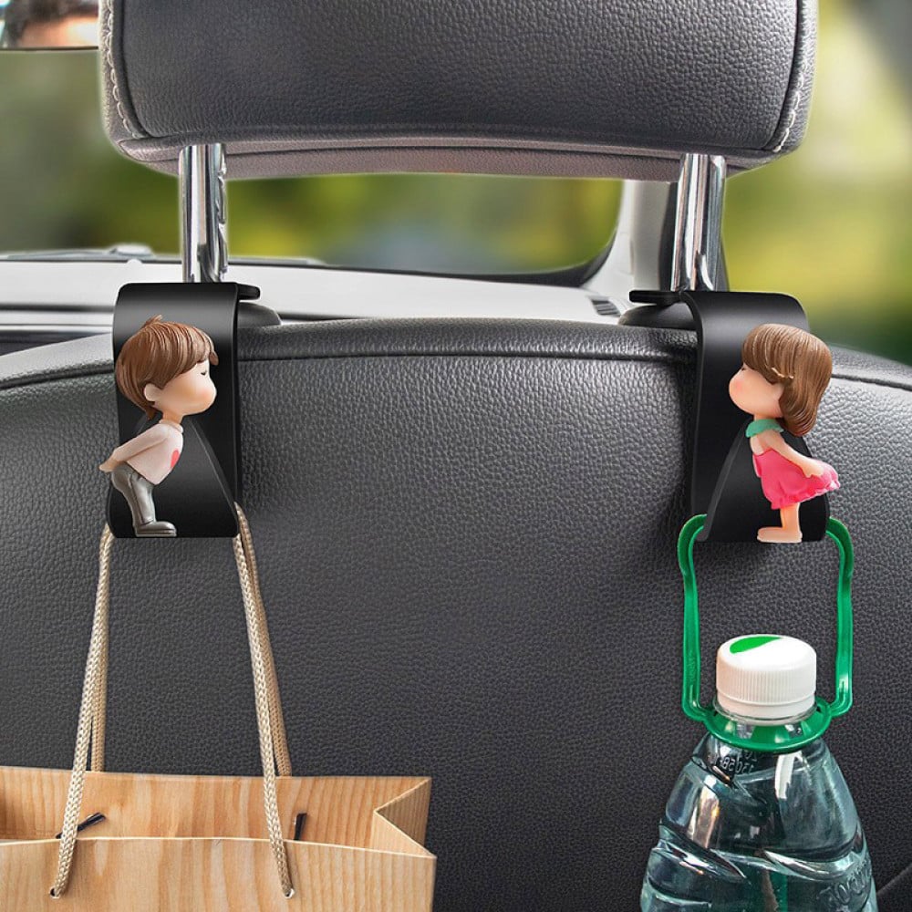 The 2pcs Universal Car Headrest Hook is a cute couple car hanger that can be used to hang and store items such as clothes in a car.