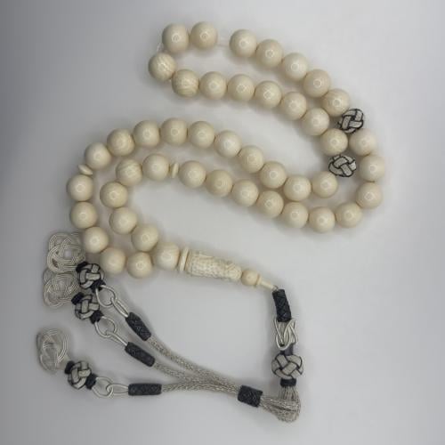 سبحه من عاج الفيل بخرز كروي و شاهد منقوش منظومه بطربزونه فضه بلون فضي فاتح و اسود بتصميم حلقي ثلاثي وعقده وسطيه باطراف ثلاثيه