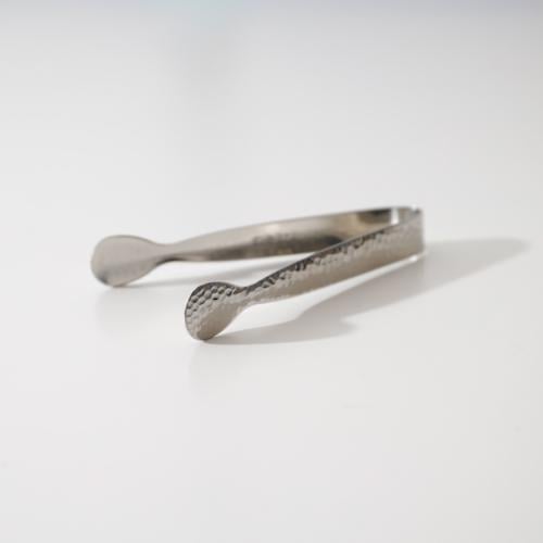 Silver-colored charcoal tongs and oud