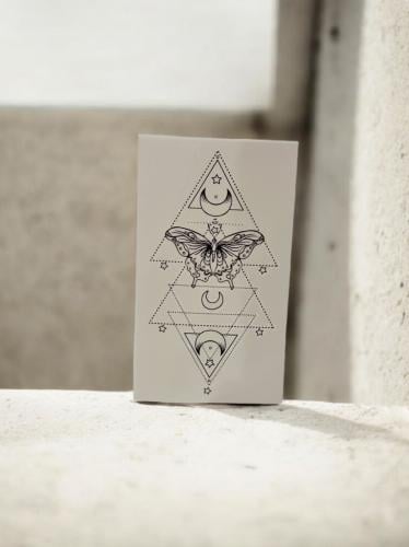 وشم مؤقت بتصميم فراشة هندسية ورموز قمرية